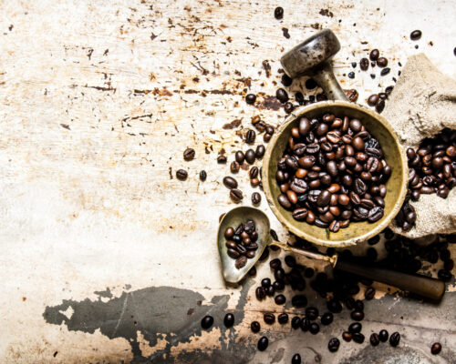 Roasted coffee in a mortar with pestle and the bag. On rustic background.